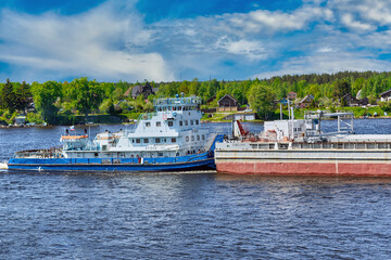 View of a tugboat pushing a heavy barge down the river along the shore