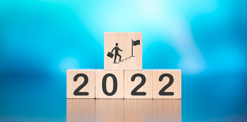 Wooden cube with concept of business target in 2022 on blue background