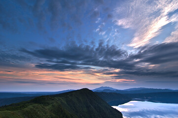 雄大な夜明けの空を湖面に映す山間の湖。日本の北海道の摩周湖。