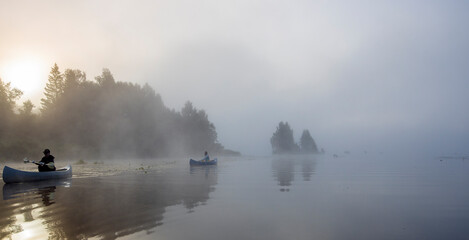 Early morning. Fog on the river. Beautiful sunrise in the summer by the river. Kayaks float in the fog.