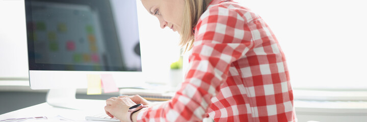 Hunched woman typing on computer keyboard at table