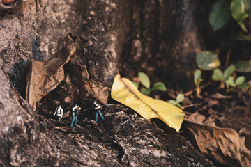 Group of miniature people hiking under tree.