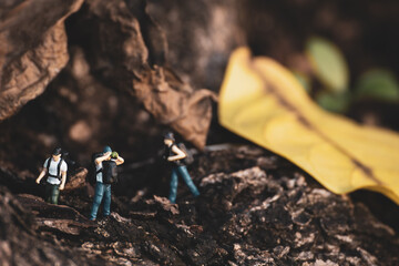 Group of miniature people hiking under tree.