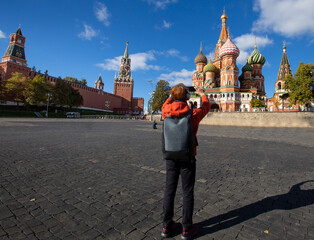 Back view of young hipster man using smartphone taking a picture in Saint Basil church at Moscow,Russia and blue sky background
