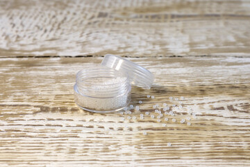 White beads for needlework. Pearl color in plastic jar. On white pine wooden boards