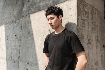 Fototapeta premium Young Asian sportsman leaning against the wall is taking a break