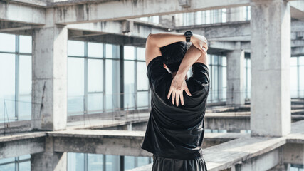 Young Asian man is doing body stretching in an abandoned reinforced concrete building