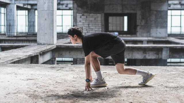 Young man is practicing running in an abandoned reinforced concrete building - Powered by Adobe