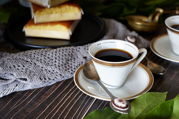 coffee in white cup on white porcelain plate on wooden table.