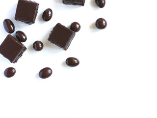 Chocolate-covered cake and chocolate-covered nuts on a white plate. Copy space. Confectionery concept.