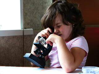 The child looks through the microscope narrowed his eyes focused examines. Children's experiences...