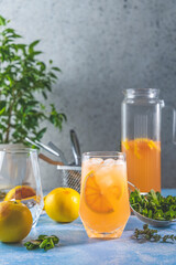 Grapefruit gin tonic cocktail, refreshing drink with ice. Cold summer citrus refreshing drink cocktail or beverage with ice, mint and thyme on blue table surface.