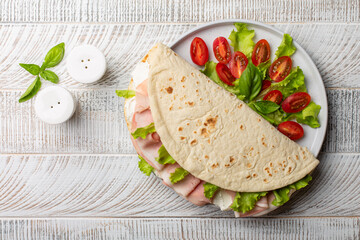 Italian summer lunch. Piadina romagnola, traditional italian flatbread with ham, soft cheese and...