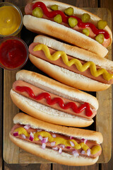 hot dogs with mustard and ketchup on wooden background