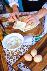image with the hands of a lady cooking traditional Romanian fried pies with cheese in traditional clothes.