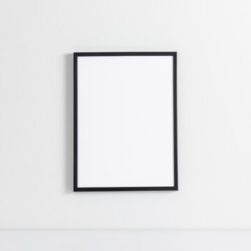 Black photo frame mockup on white wall. Front view