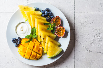 Fresh fruit charcuterie dessert grazing platter on white plate, light tiles background. Vegan food...