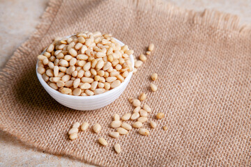 Organic Pine nuts in a bowl on a jute napkin