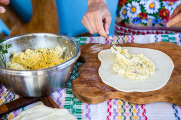 image with the hands of a lady cooking traditional Romanian fried pies with cheese in traditional clothes.