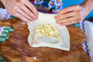 image with the hands of a lady cooking traditional Romanian fried pies with cheese in traditional clothes.