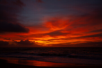 Fototapeta na wymiar Bright orange sunrise over beach in Hawaii