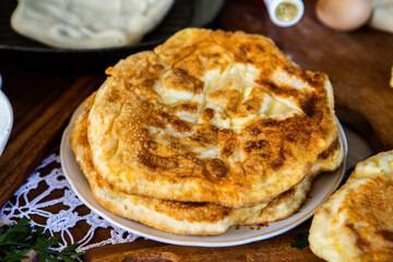 image with the hands of a lady cooking traditional Romanian fried pies with cheese in traditional clothes.