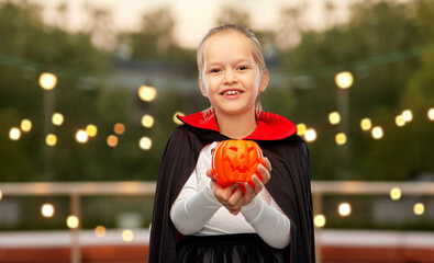 halloween, holiday and childhood concept - happy smiling girl in black dracula cape or costume with...
