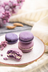 Obraz na płótnie Canvas Purple macarons or macaroons cakes with cup of coffee on a gray wooden background. Side view, selective focus.