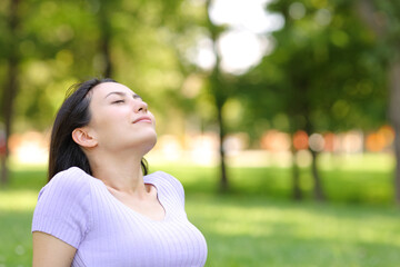 Asian woman breathing fresh air sitting in a park