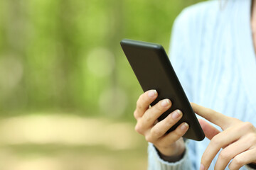 Close up of a woman hands using smart phone in a forest