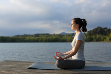 Fototapeta na wymiar Profile of a woman doing yoga exercise in a lake