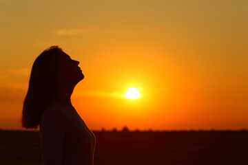 Silhouette of a female breathing fresh air at sunset