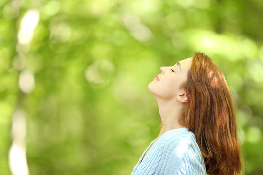 Redhead woman breathing fresh air in a forest