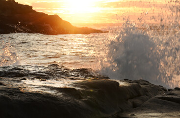 Dawn on the ocean. Splashing waves crashing against the coastal rocks against the backdrop of the rising sun. USA. maine.
