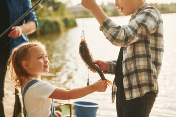 Father with son and daughter on fishing together outdoors at summertime