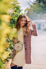Outdoor autumn portrait of young beautiful woman in trendy outfit. Smiling girl with gorgeous blond hair. Fashionable warm plaid coat, knitted white dress.