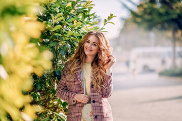Outdoor autumn portrait of young beautiful woman in trendy outfit. Smiling girl with gorgeous blond hair. Fashionable warm plaid coat, knitted white dress.