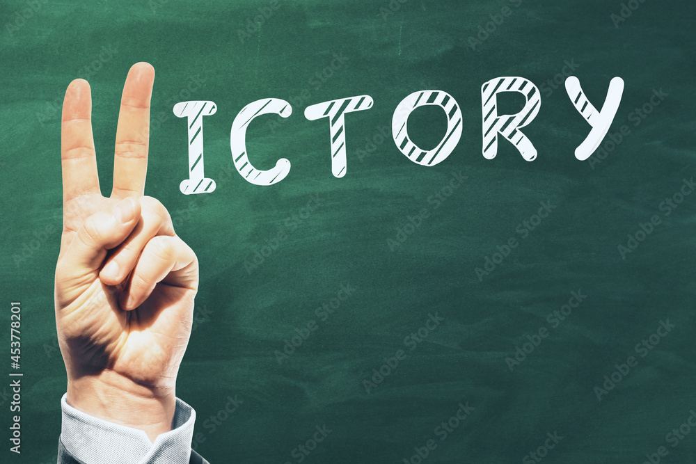 Poster hand with peace sign gesture replacing letter v in victory word on chalkboard background with mock u