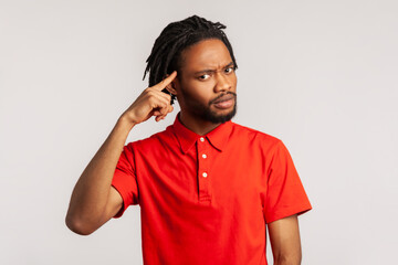 Serious bearded man with dreadlocks wearing red casual style T-shirt, looking at camera holding...