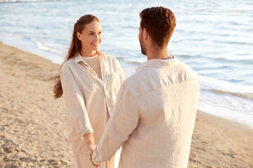 Fototapeta premium leisure, relationships and people concept - happy couple holding hands on summer beach