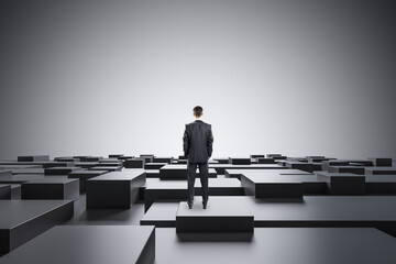 Businessman standing on abstract gray geometric maze background with mock up place. CEO and future concept.