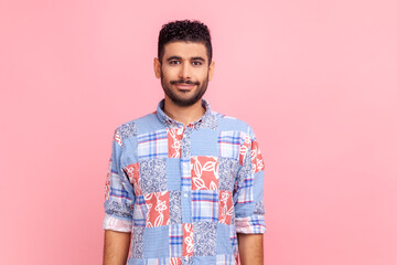 Portrait of handsome bearded man wearing casual style blue shirt posing with positive facial expression, looking at camera with smile. Indoor studio shot isolated on pink background.