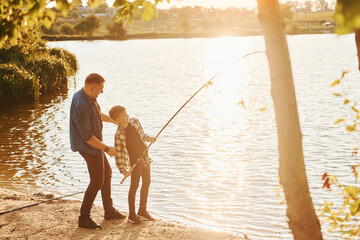 With catch. Father and son on fishing together outdoors at summertime