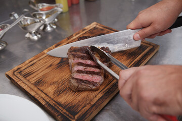 Chef slicing beef steak on a wooden cutting board