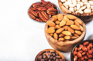 Nuts in bowls. Almonds, hazelnuts, walnuts and other. Healthy food snack mix on white table, top view, copy space