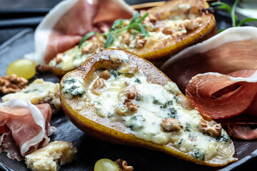 Appetizer with pear baked with blue cheese, nuts and honey, prosciutto. Food recipe background....