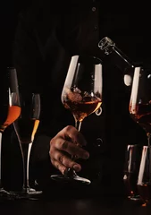 Rolgordijnen Sommelier pouring rose wine into glass at wine tasting in winery, bar or restaurant. Black toned image © 5ph