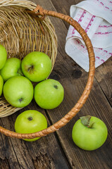 Ripe green apples in the basket on the wooden table