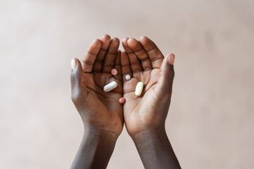 Pair of black palms holding different pharmaceutical formulations for oral treatment; African...