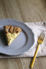 Slice of cheese and leek quiche on wooden table. Selective focus.